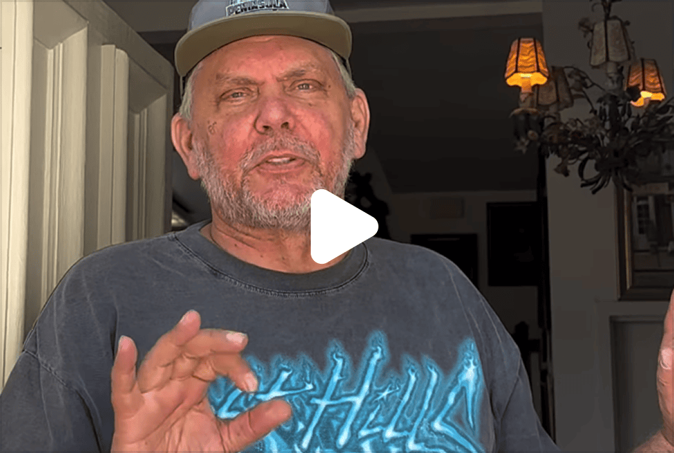 A man with a gray beard and a "PENINSULA" baseball cap gestures with his right hand, a play button overlayed.